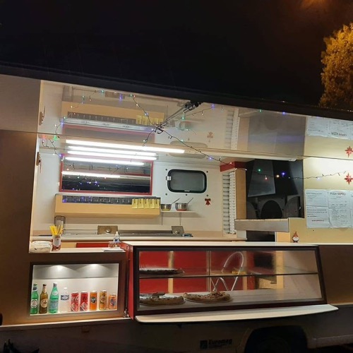 Le comptoir ouvert du food truck Pizza Napoli, photographié de nuit.