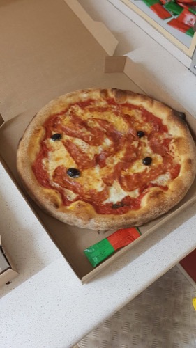 Pizza garnie dans sa boîte à emporter.