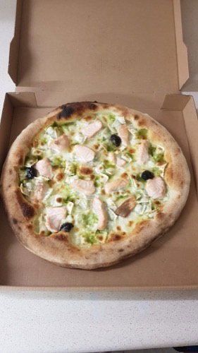Pizza garnie avec des olives, présentée dans sa boîte.