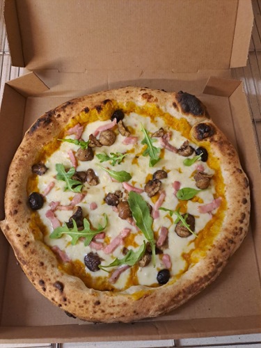 Pizza garnie, photographiée de dessus dans sa boîte.