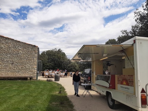 Le food truck Pizza Napoli installé en extérieur, près d'un bâtiment en pierre.