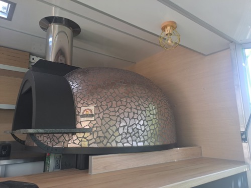 Le four à bois habillé de mosaïque dans le food truck.