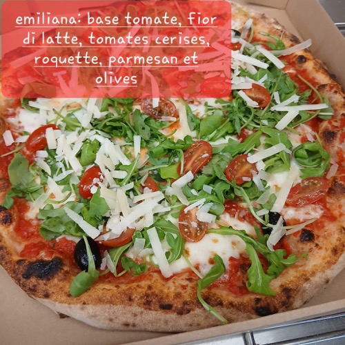 Gros plan sur une pizza garnie de roquette et de copeaux de fromage.